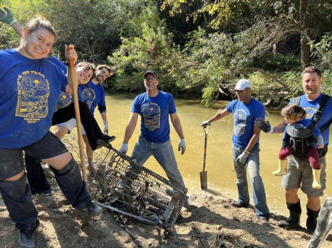 A group of volunteers with It's M Park Day Fall tshirts cleaning out a creek for It's My Park Day Fall 2022