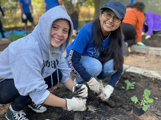 Two young volunteers planting in a garden for It's My Park Day Fall 2022